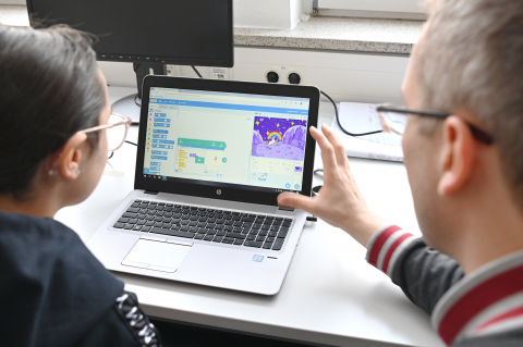Beim IT-Bootcamp für Kids programmierten die Teilnehmenden selbst kleine Software-Funktionen. Unterstützt wurden sie dabei von Tutor*innen des Fachbereichs Informatik. Mädchen und Experte vor dem Laptop
